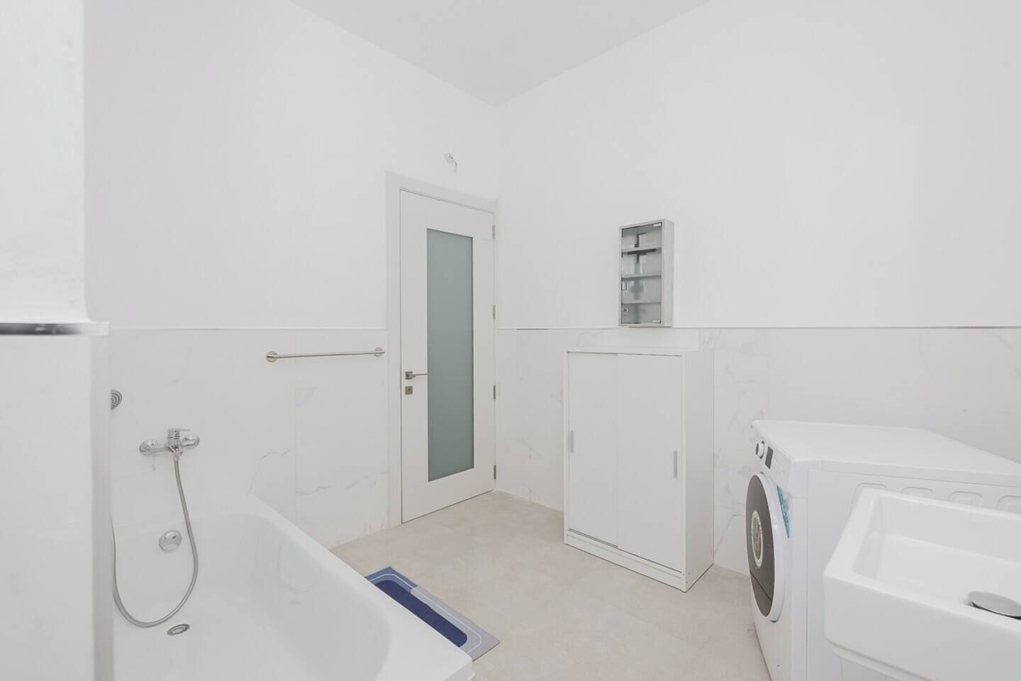 A modern bathroom with a shower, a toilet, and a washing machine.