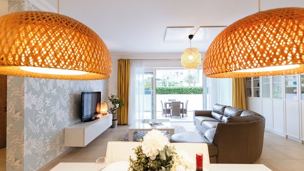 A modern living room with a sofa, a TV, and a dining table with a vase of flowers. - 102 Seafront 3Bed Sliema with pool by Homely (Tas-Sliema)