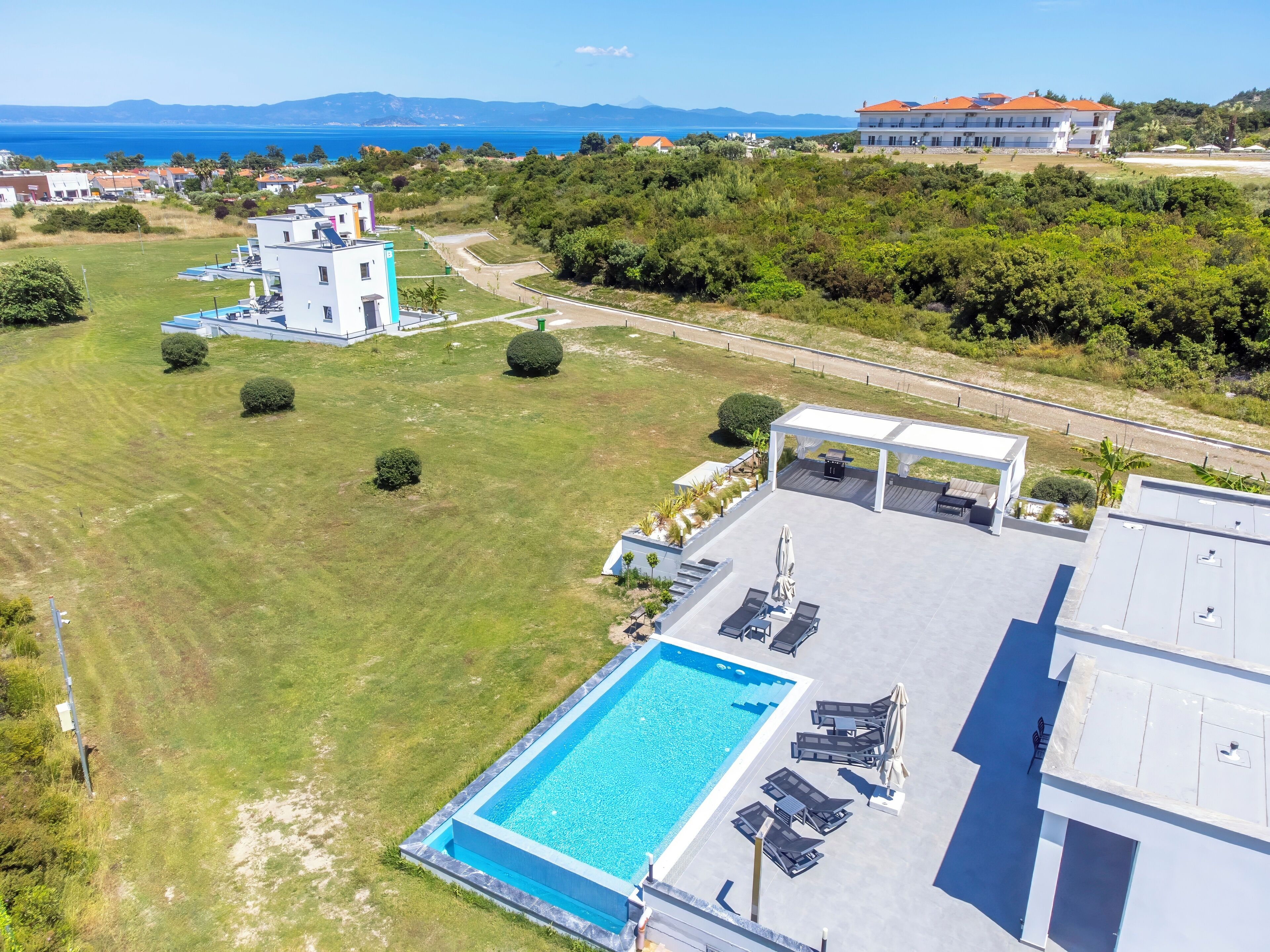 Ein modernes Hotel mit Pool auf dem Dach, einer überdachten Terrasse und Blick aufs Meer.