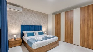 A modern bedroom with a wooden bed frame, a blue upholstered headboard, and a large wardrobe with vertical wooden panels.