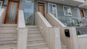 A modern building with a staircase leading to a door, multiple balconies, and a sign that reads "BURSELEY."