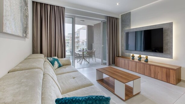 A modern living room with a sofa, a coffee table, and a TV mounted on the wall.