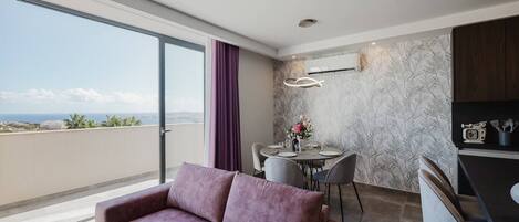 A modern room with a purple sofa, a dining table with chairs, and a kitchen area with a microwave and utensils.