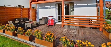 A wooden deck with outdoor furniture and flower planters.