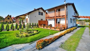 Uma casa moderna de dois andares com varanda, um jardim bem cuidado e céu claro.