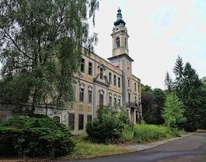 A historic building with a prominent tower and arched windows, surrounded by dense greenery. - Doppelhaushalfte, Schonwalde (Schönwalde-Glien)