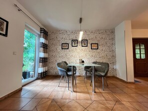 Un comedor con pared de ladrillo, una mesa de vidrio y cuatro sillas.