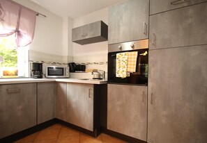 A kitchen with a microwave, oven, and cabinets. - Doppelhaushalfte, Schonwalde (Schönwalde-Glien)