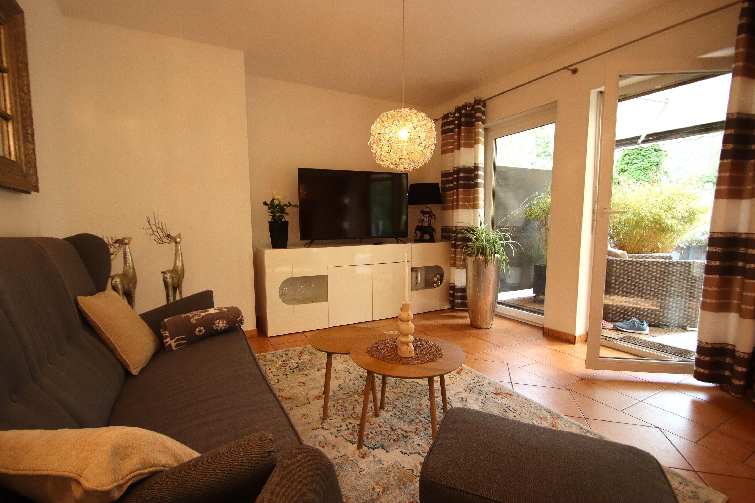 Una sala de estar con un sofá, una mesa de centro, un televisor y una planta decorativa.