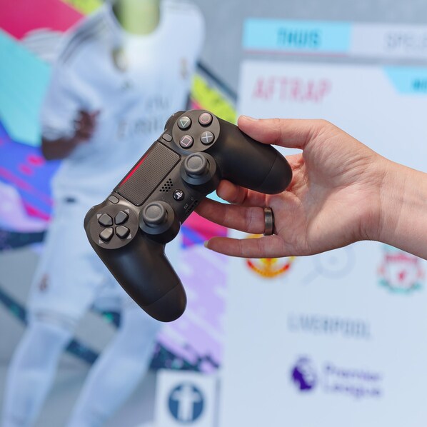 A hand holding a PlayStation controller.