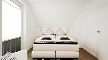 A bedroom with a bed, a window, and a door.