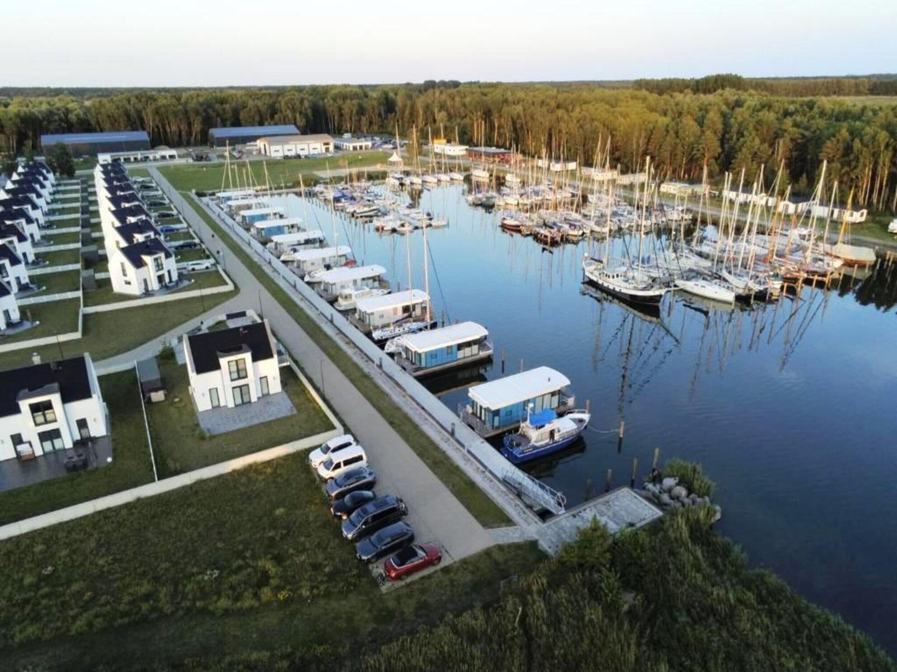 A marina with boats docked, a row of mobile homes, and a grassy area.