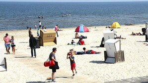 Une plage où des gens se prélassent au soleil, une tente et une glacière sur le sable.