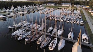 Un port de plaisance où de nombreux bateaux sont amarrés, entouré de bâtiments et de verdure.