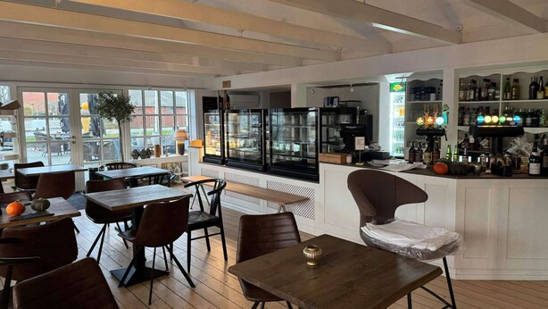 A restaurant with wooden tables and chairs, a bar area with shelves of bottles, and a large window with a view of the outside. - Hotel Fanobad With Free Water Park Access (Fano)