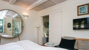 A bedroom with a bed, a round mirror, a television, and a door leading to a bathroom. - Hotel Fanobad With Free Water Park Access (Fano)