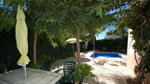 An outdoor patio area with a stone floor, a pool, and green chairs. - SAONA VILLAS (VN DO) : villa 6 personnes, 500 m de la mer, climatisation, wifi (Tres Calas)