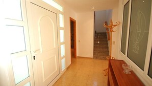 A hallway with a white door, a wooden bench, and a framed picture on the wall. - SAONA VILLAS (VN DO) : villa 6 personnes, 500 m de la mer, climatisation, wifi (Tres Calas)
