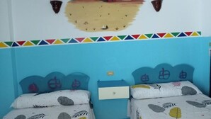 Une chambre avec deux lits, une fresque murale et une bordure colorée.