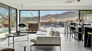 Un salon moderne doté d’une grande fenêtre, d’une cheminée et d’un coin repas offrant une vue sur les montagnes.