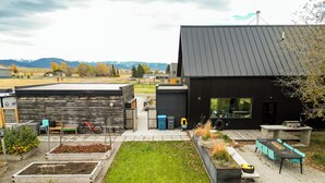 Une maison moderne dotée d’une grande terrasse, d’un espace salon extérieur et de jardinières surélevées.