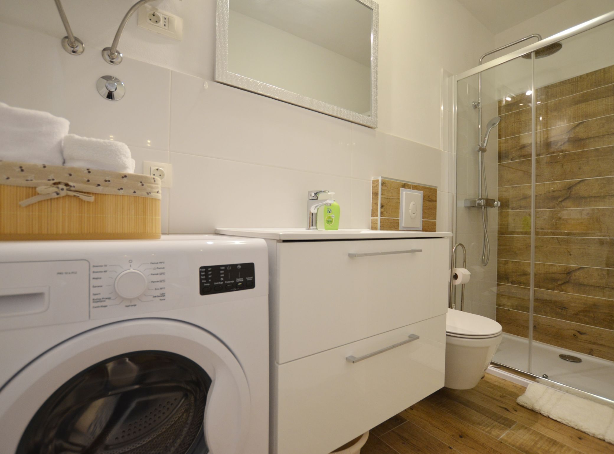 Ein modernes Badezimmer mit Waschmaschine, Toilette und Duschkabine.