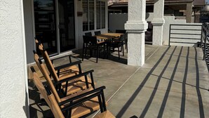 Eine Außenpatio mit Tisch und Stühlen, einem Deckenventilator und Blick auf benachbarte Gebäude.