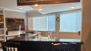 A bar area with a sign reading "SALON" above a counter, two wooden chairs, and a window with blinds. - Dock Holiday – The Keys Favorite | Wild West River Escape (Parker)