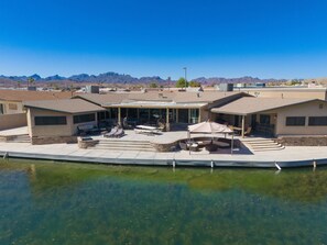 A waterfront property with a covered patio area, outdoor seating, and a pool. - Dock Holiday – The Keys Favorite | Wild West River Escape (Parker)