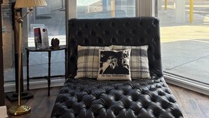 A black leather sofa with a tufted backrest and a plaid pillow with a quote. - Dock Holiday – The Keys Favorite | Wild West River Escape (Parker)