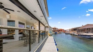 Ein Hotel am Wasser mit einer überdachten Terrasse, Außenbestuhlung und Booten, die an der Uferlinie liegen.
