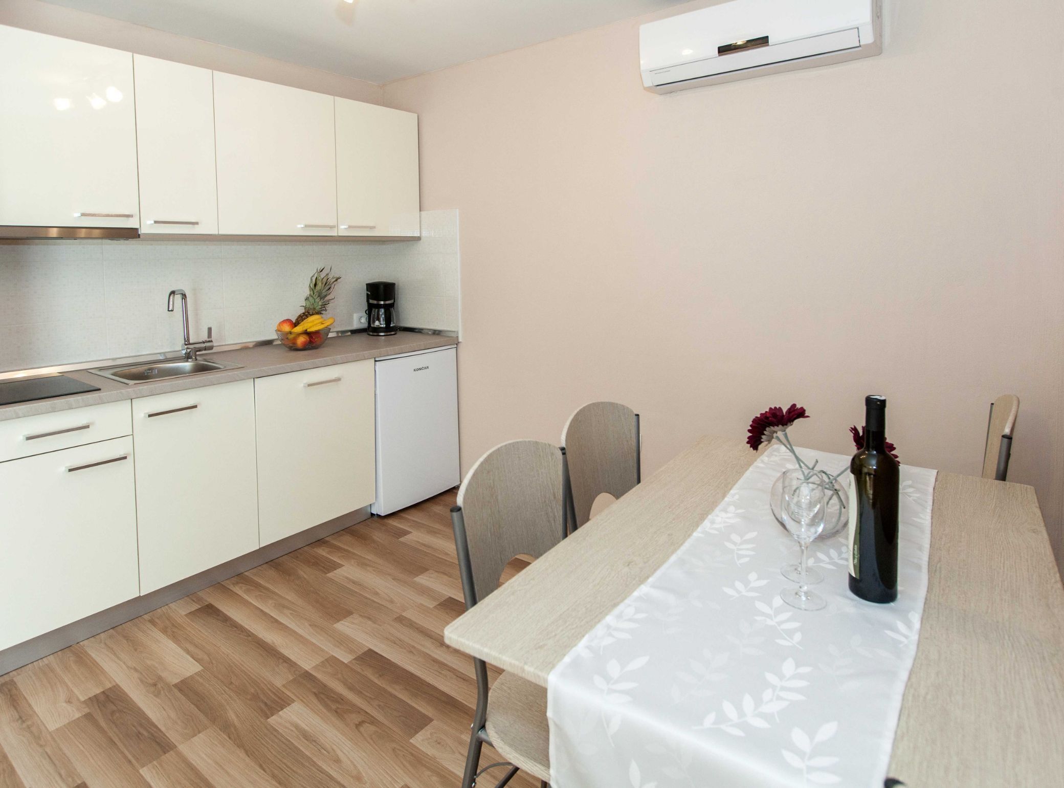 Una cocina moderna con armarios blancos, lavavajillas integrado y una cafetera sobre la encimera.