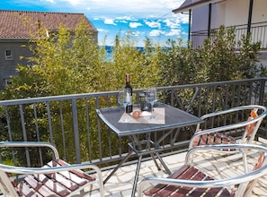 A balcony with a table, two chairs, and a bottle of wine. - Beachfront Crikvenica Apartments With Sea View (Crikvenica)