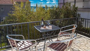 A balcony with a table and chairs, overlooking a residential area and the sea. - Beachfront Crikvenica Apartments With Sea View (Crikvenica)
