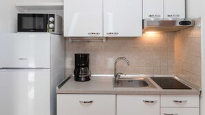 A modern kitchen with white cabinetry, a built-in microwave, a coffee maker, a sink, and a stainless steel range hood. - Beachfront Crikvenica Apartments With Sea View (Crikvenica)
