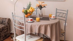 A dining table with a fruit bowl, two glasses of orange juice, and a cup on a tablecloth. - Beachfront Crikvenica Apartments With Sea View (Crikvenica)
