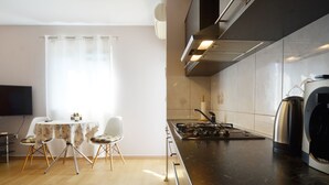 A modern kitchen with a black countertop, stainless steel appliances, and a dining area with a table and chairs. - Charming Retreat Near Rovinj With Private Balcony (Rovinj)