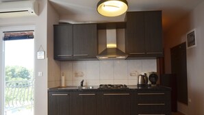 A modern kitchen with dark cabinetry, a stainless steel sink, and a gas stove. - Charming Retreat Near Rovinj With Private Balcony (Rovinj)