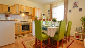 Una cucina compatta con mobili in legno, un fornello e un'area pranzo con quattro sedie verdi e un tavolo apparecchiato.