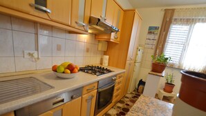 Una cucina con mobili in legno, un fornello a gas, forno integrato e pavimento decorato.
