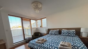 Un dormitorio con una cama grande, una silla, una mesita de noche y un candelabro.