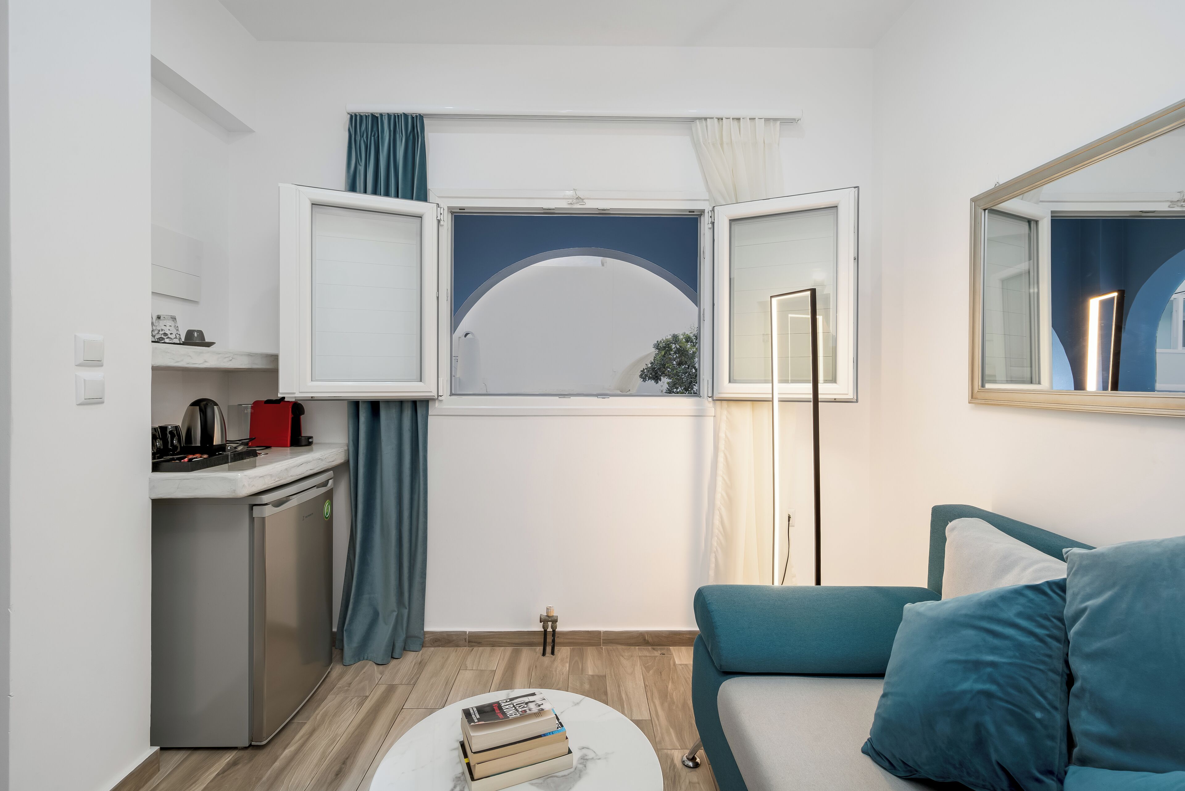 A compact living space with a kitchenette, a sofa, a coffee table, and a window with curtains.