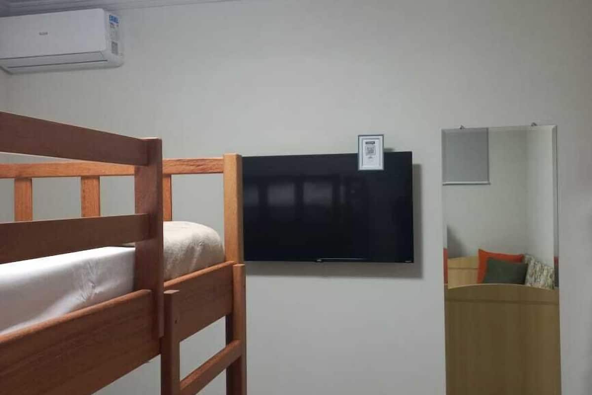 A bunk bed room with a mounted TV and a mirror on the wall.