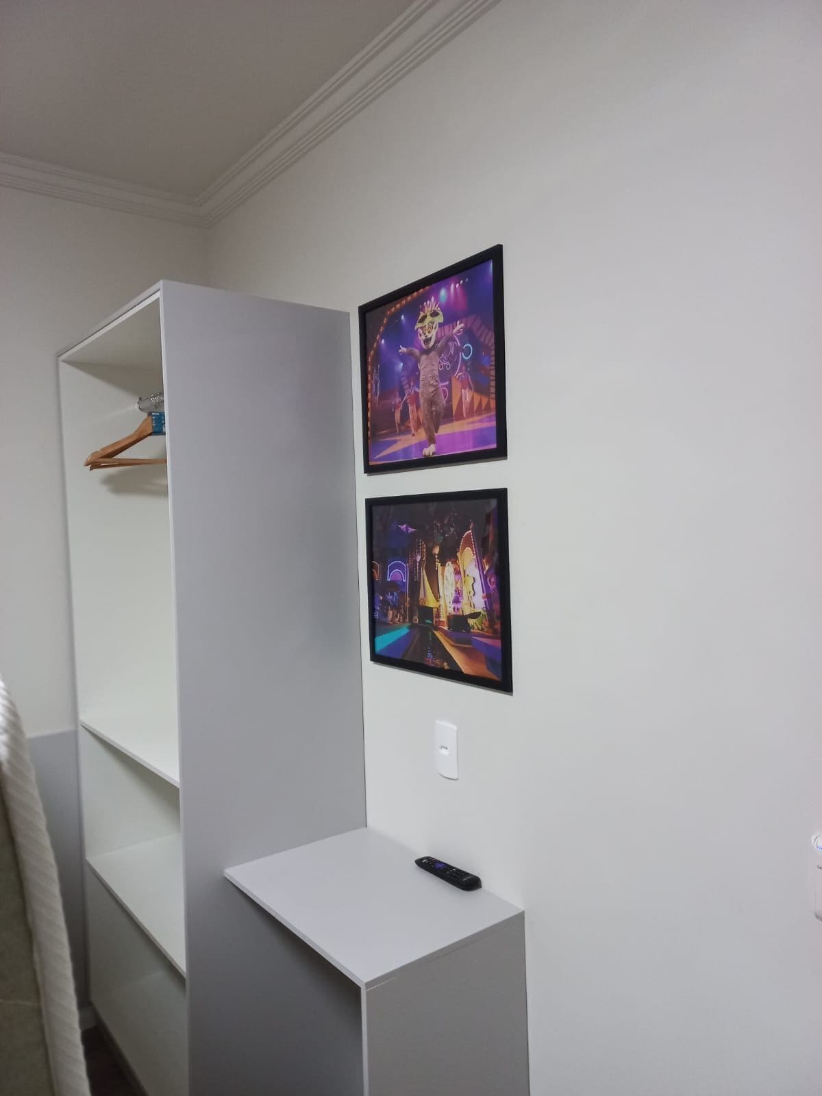 Una habitación con un armario blanco, un escritorio blanco y dos cuadros en la pared.