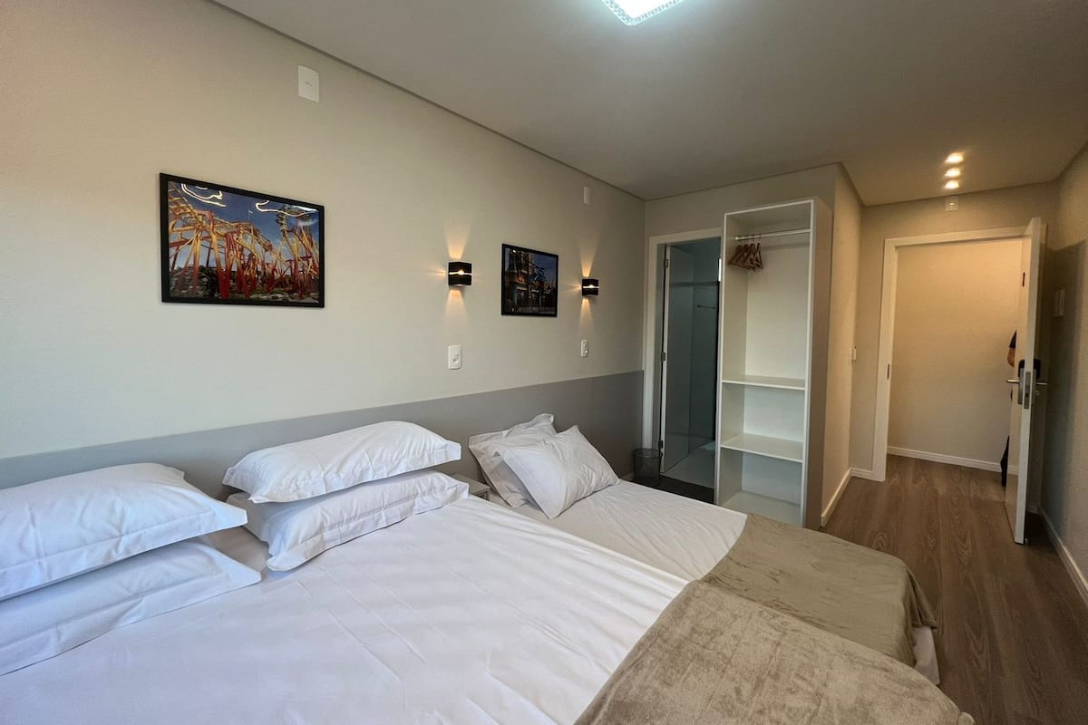 A hotel room with two beds, a walk-in closet, and a shower area.