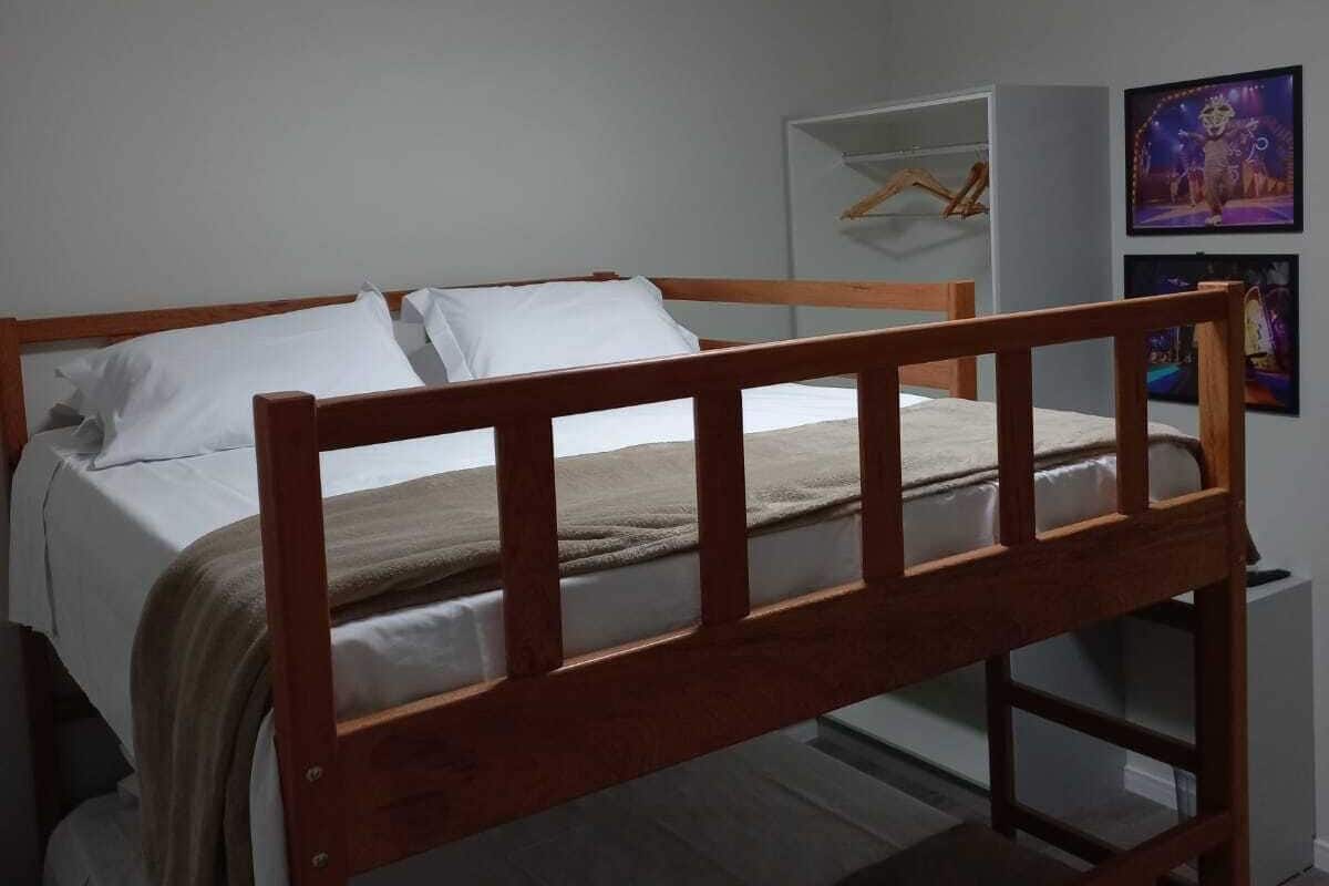 A single bed with a wooden frame, white bedding, and a bedside table with a lamp.