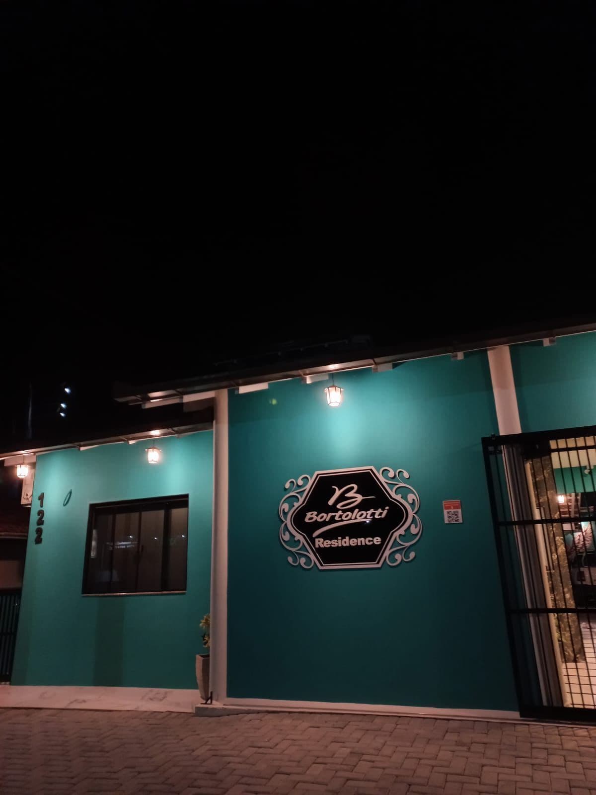 A teal-colored building with a sign reading "Bortolotti Residence" and a black gate.