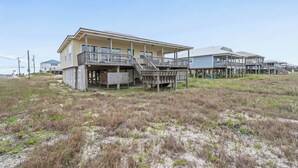 A beachfront property with a main building and several smaller structures, including a covered porch and a staircase leading to a deck. - Sound Front Home with both Gulf & Sound Views! (Dauphin Island)