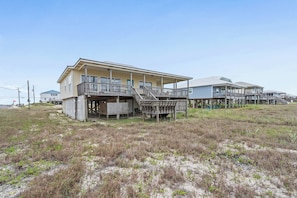 A beachfront property with a main building and several smaller structures, including a covered porch and a staircase leading to a deck.