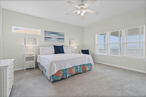 A bedroom with a bed, a ceiling fan, a window with blinds, and wall art.